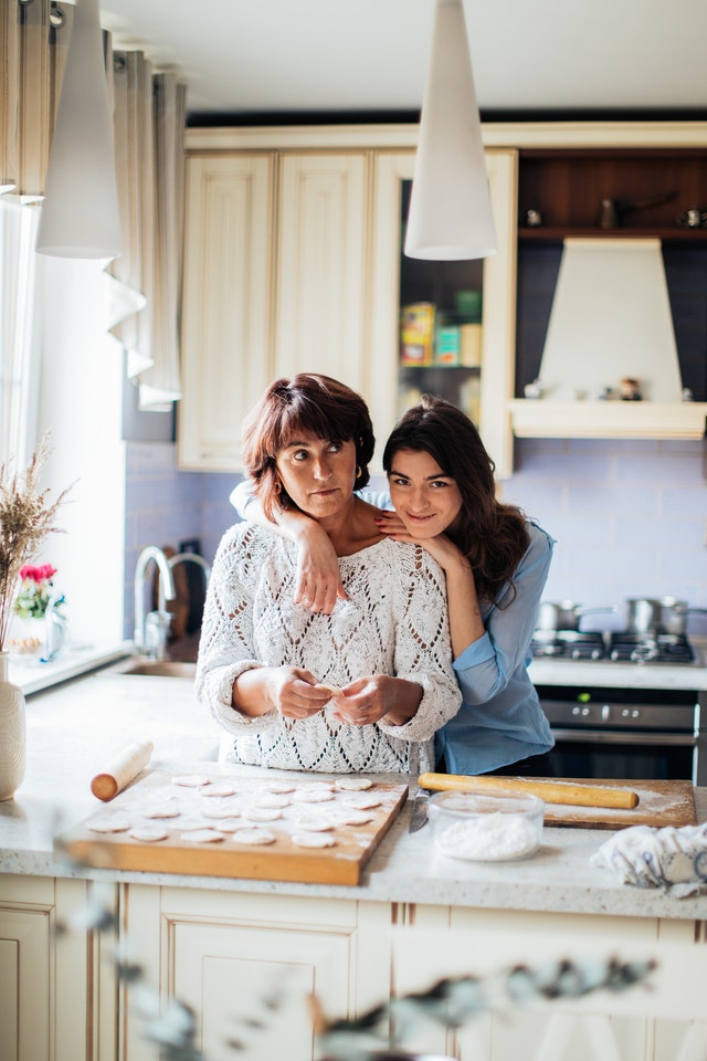 young girl hugging her mother in the kitchen
